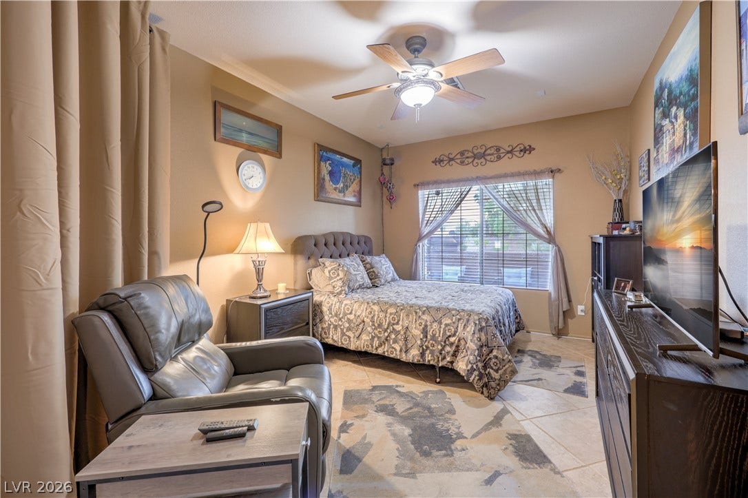 10474 Rustyville Court, Las Vegas, NV 89129 Relax in this tranquil bedroom downstairs, featuring tile flooring and a refreshing ceiling fan.