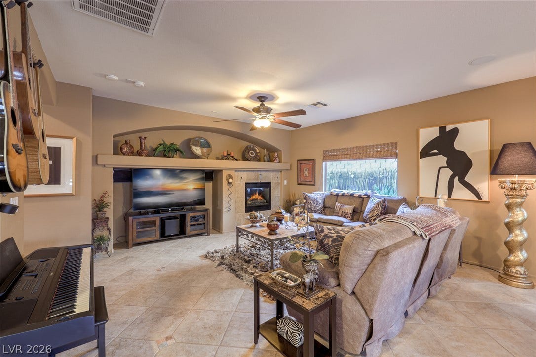 10474 Rustyville Court, Las Vegas, NV 89129 A comfortable living space featuring a cozy fireplace, tiled flooring, and elegant built-in shelves.