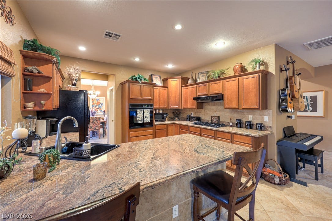 10474 Rustyville Court, Las Vegas, NV 89129 A gourmet kitchen offers rich wood cabinetry, granite countertops, and modern appliances for culinary delight.