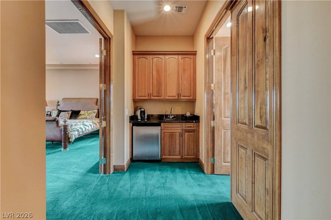 Rich wood cabinetry and a convenient wet bar anchor this hallway alcove.