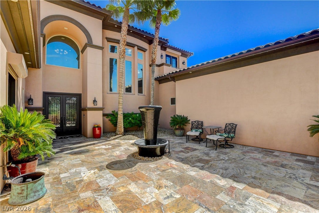 An inviting gated courtyard greets guests with slate tile flooring and a central water fountain.