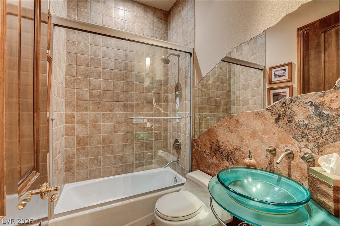 Tiled walls and a unique natural stone backsplash surround this custom bathroom vanity.