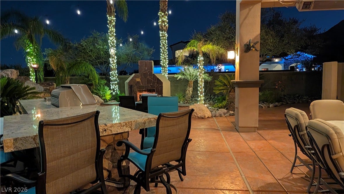 An inviting outdoor kitchen and stone fireplace anchor this expansive, covered patio retreat.