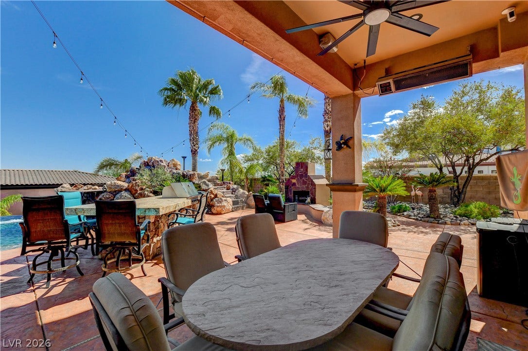 An expansive covered patio overlooks a beautiful backyard oasis complete with pool and fireplace.