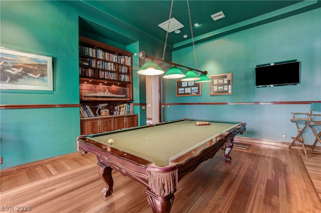Rich hardwood flooring and integrated library shelving define this expansive recreation space.