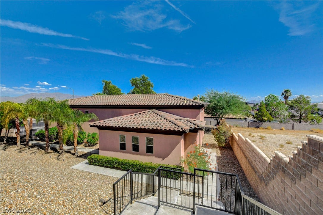 Concrete steps descend toward a low-maintenance gravel yard with a tile-roofed structure.