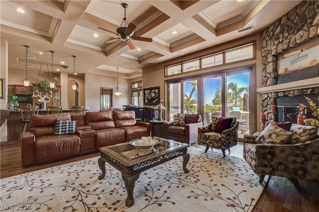 Exquisite coffered ceilings and a towering stone fireplace define this expansive living area.