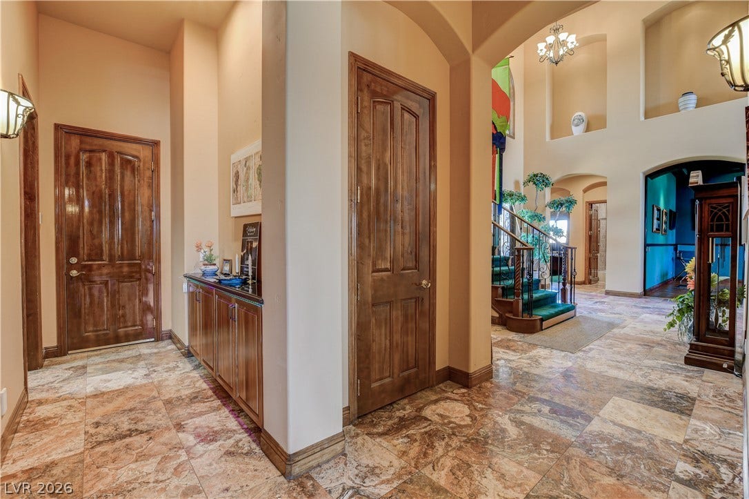 Gleaming stone tile flooring and soaring arched passages create a grand entryway experience.