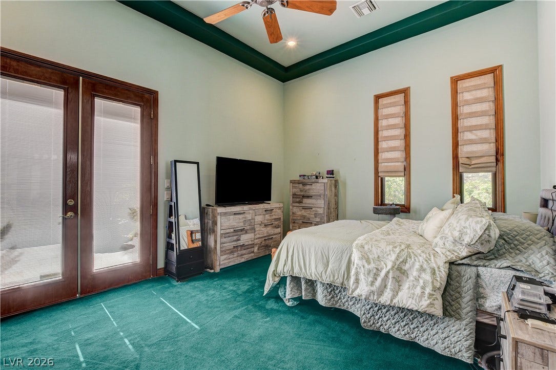 Double doors open to the outdoors in a bedroom featuring high tray ceilings.