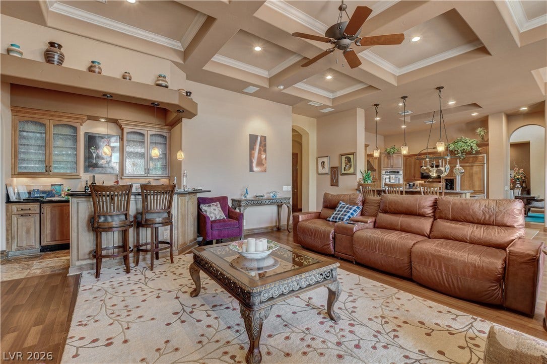 An elegant coffered ceiling and built-in wet bar define this spacious living area.