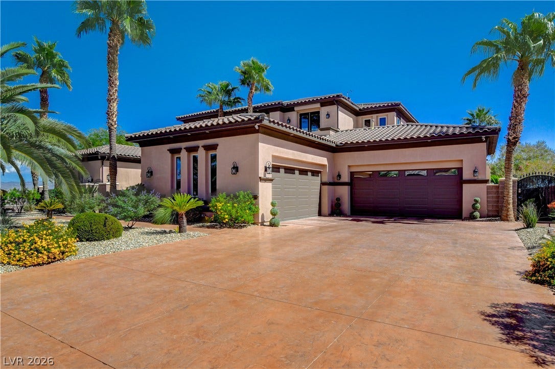 A spacious stamped concrete driveway leads toward the grand multi-car garage of this stucco home.