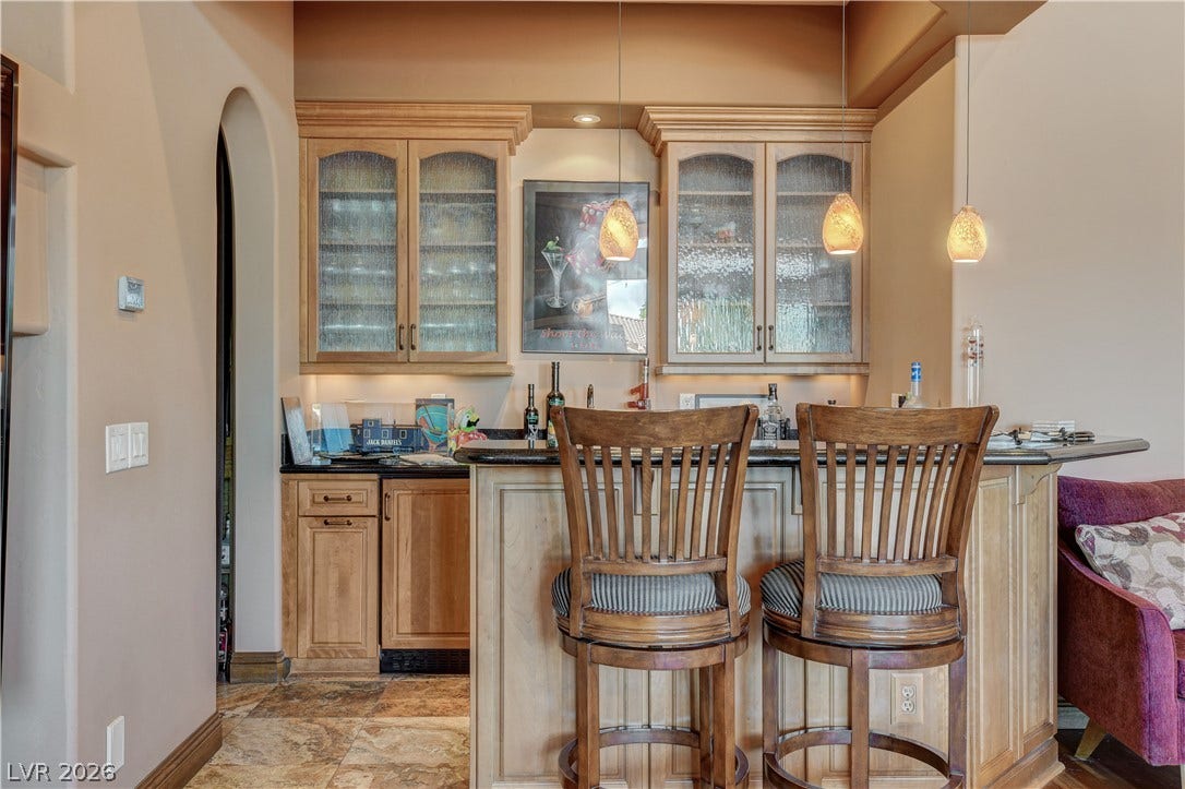 Richly crafted wood cabinetry and stone counters define this custom home wet bar.