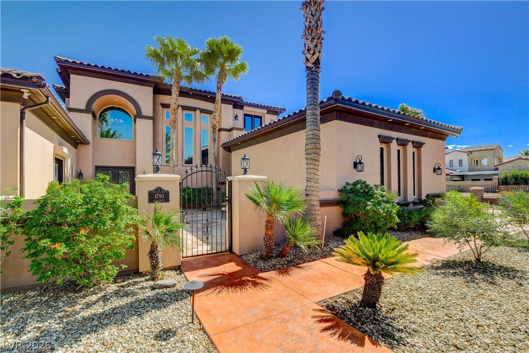 Palm trees flank a gated entryway leading into a private front courtyard.