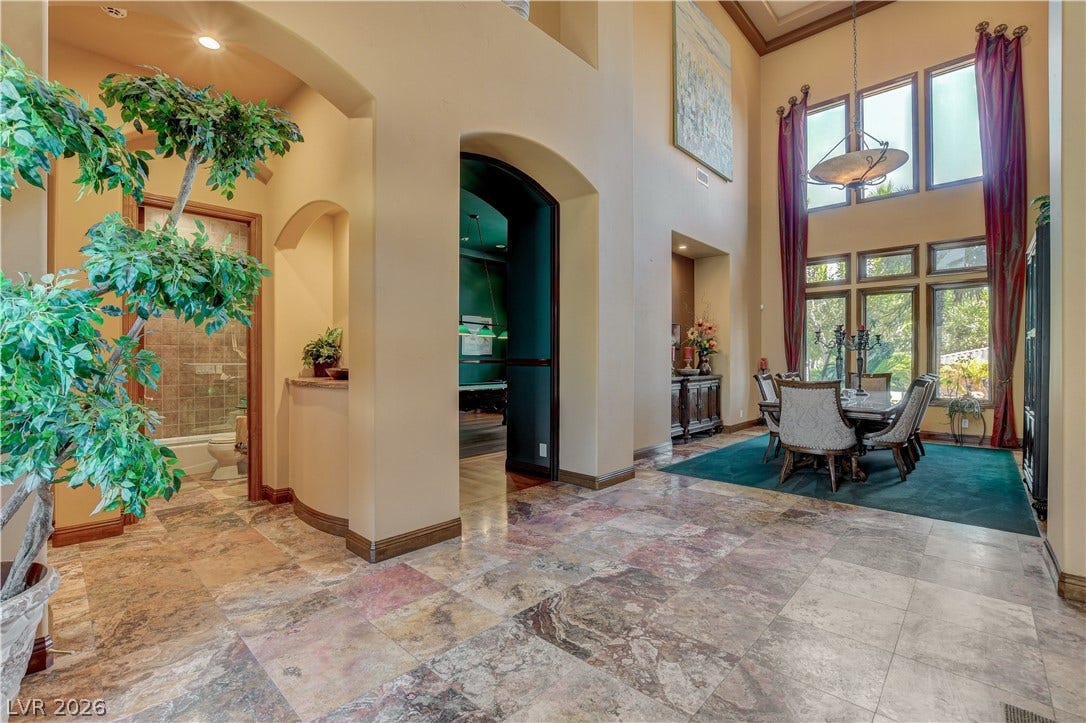 Polished stone tile flooring runs from the grand entry foyer into a double-height dining room.