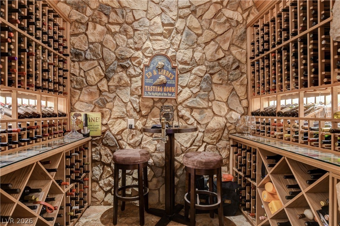 Floor-to-ceiling stone walls and custom wooden storage racks define this private wine cellar.