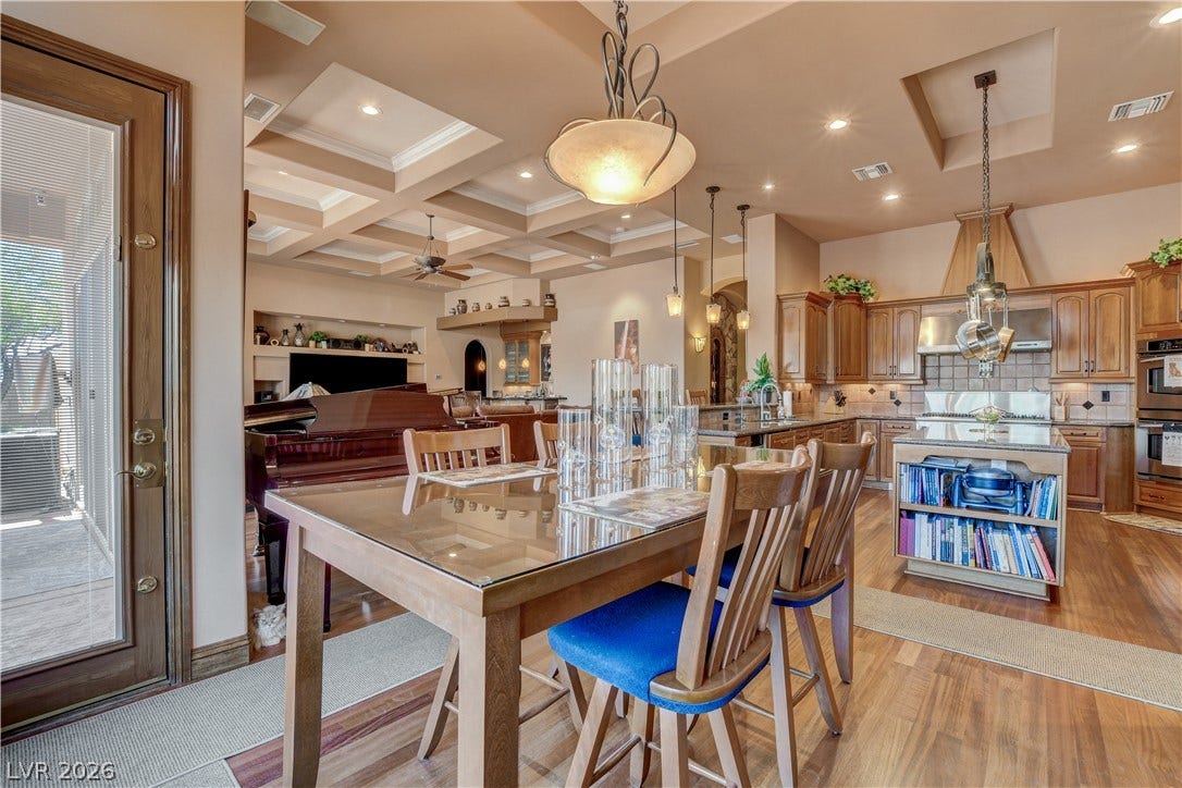 Rich wood flooring anchors this open-concept layout beneath beautifully detailed coffered ceilings.