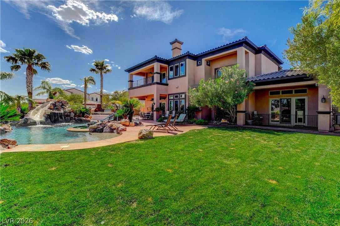 A spacious green lawn sits beside a resort-style swimming pool with a custom water slide.