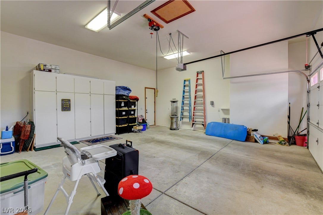 A spacious garage features durable concrete flooring, built-in storage cabinets, and high ceilings.