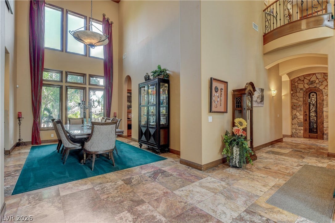 Towering windows illuminate the tiled dining space and adjacent open foyer.