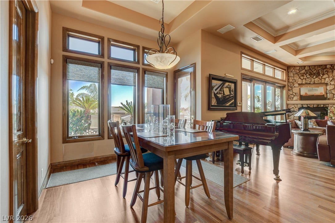 Rich hardwood floors and elegant tray ceilings define this welcoming open dining space.