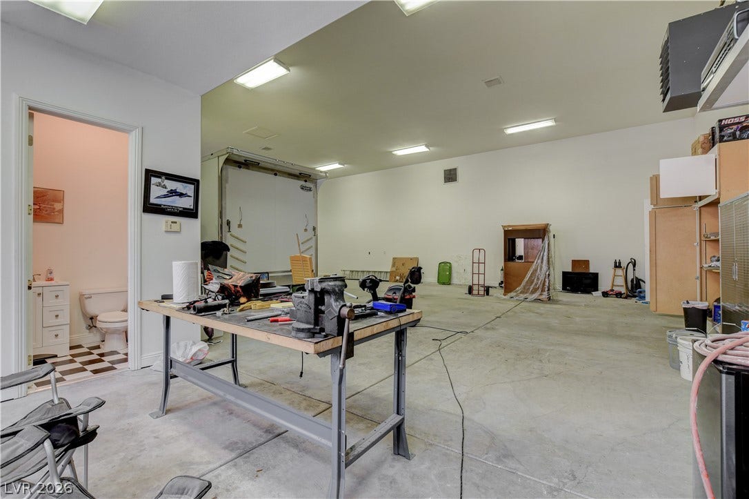 An oversized workshop featuring durable concrete flooring and high ceilings provides abundant functional workspace.