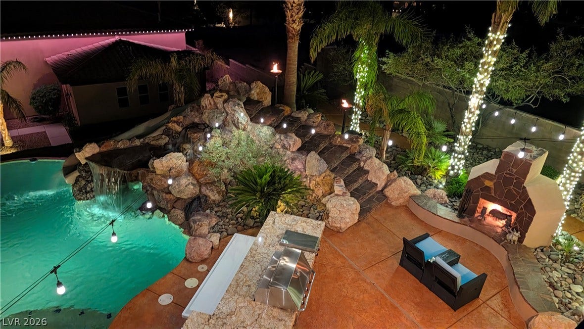 An inviting backyard oasis features a rock-scaped swimming pool with a waterfall and custom stone fireplace.