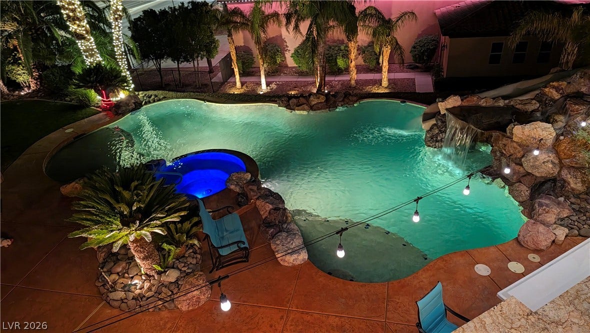An inviting backyard oasis features a custom swimming pool paired with a bubbling spa.