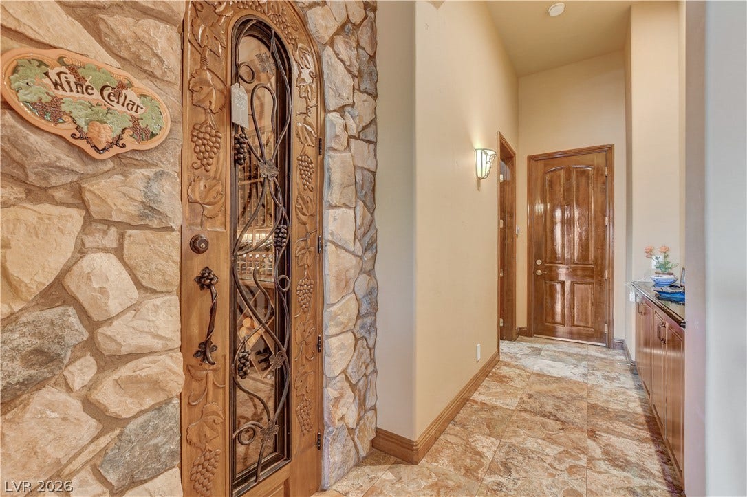 An arched custom wooden door framed in stone masonry leads to the private wine cellar.