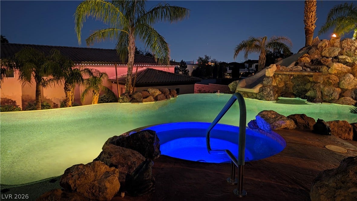 Custom stone elements and integrated lighting define this resort-style pool and spa oasis.