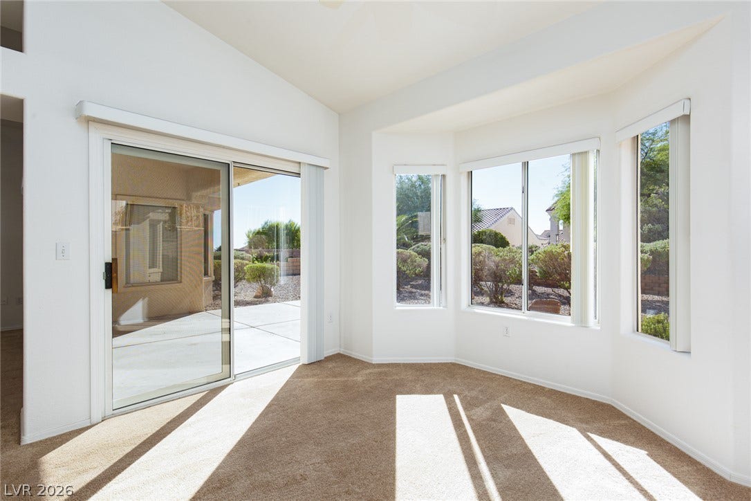 10725 Windledge Avenue, Las Vegas, NV 89134 Angled windows and a sliding glass door fill this carpeted living space with natural light.