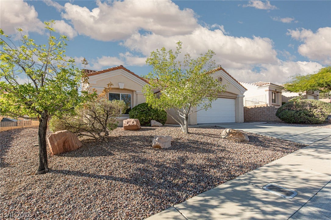 10725 Windledge Avenue, Las Vegas, NV 89134 Desert landscaping and mature plantings frame this classic stucco home with an attached garage.