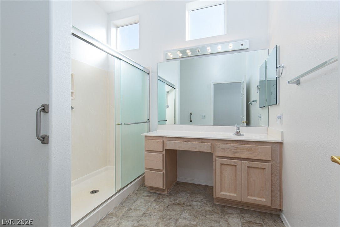 10725 Windledge Avenue, Las Vegas, NV 89134 Natural light pours through high transom windows into this bathroom featuring a glass shower enclosure.