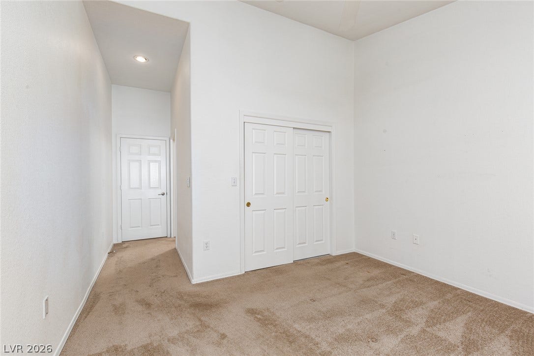 10725 Windledge Avenue, Las Vegas, NV 89134 A spacious bedroom features towering ceilings, neutral carpeting, and a large sliding closet.