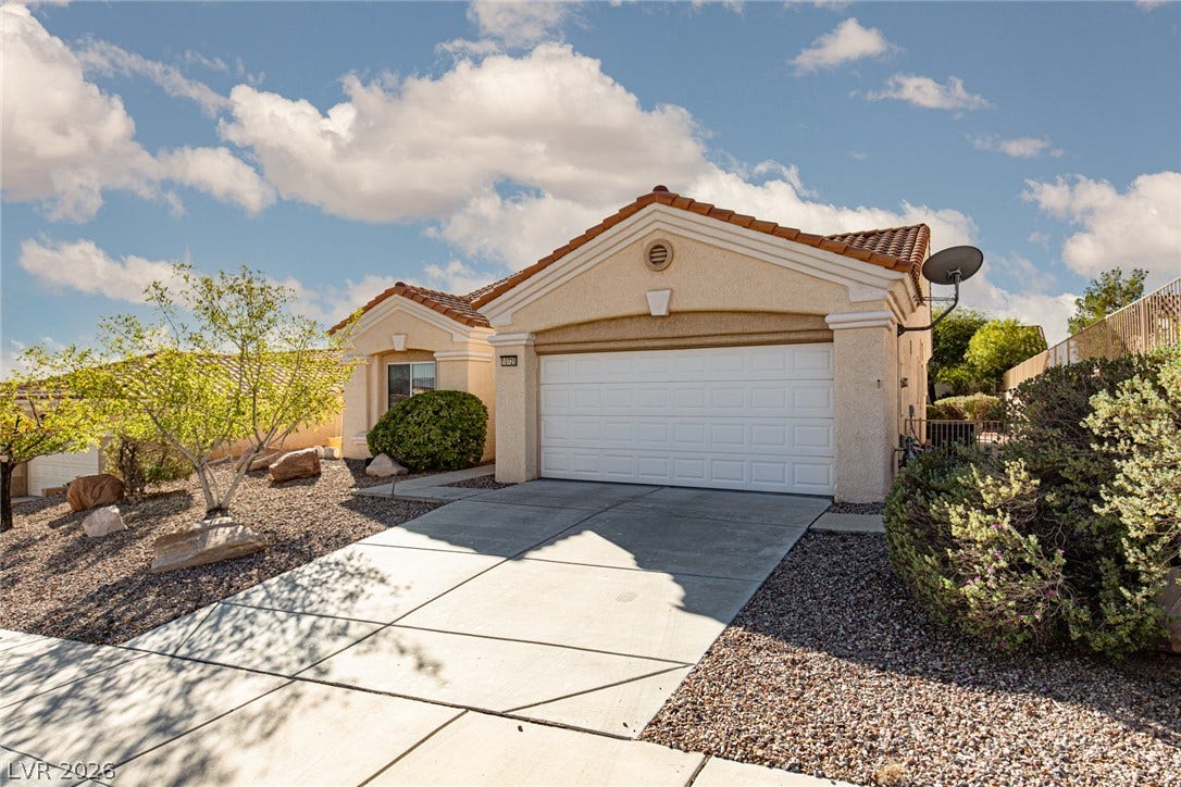 10725 Windledge Avenue, Las Vegas, NV 89134 A classic stucco exterior features a tile roof and a concrete driveway leading to the garage.