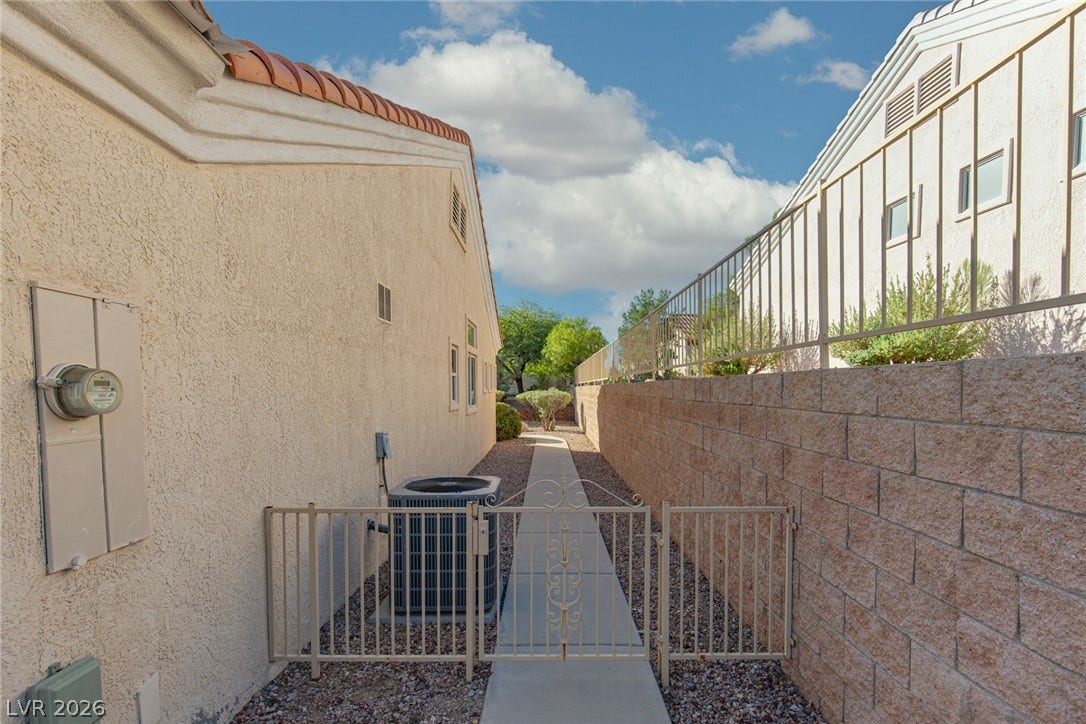 10725 Windledge Avenue, Las Vegas, NV 89134 A paved walkway runs alongside the stucco exterior under a clear blue sky.