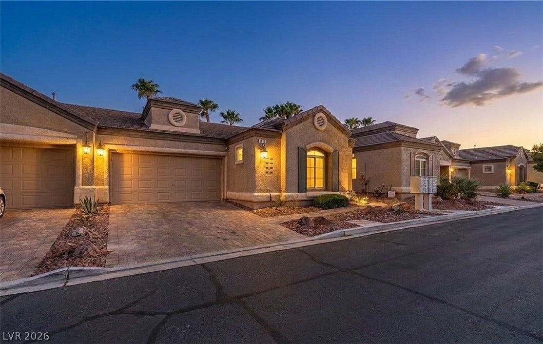 6163 Bayard Street, Las Vegas, NV 89148 Warm exterior lighting highlights this elegant stucco home with a paved driveway.