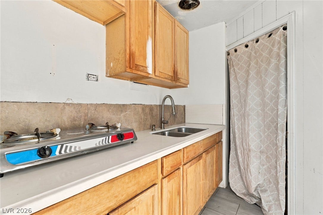 2521 Perliter Avenue, North Las Vegas, NV 89030 Natural wood cabinetry aligns with tiled flooring and a neutral backsplash in this kitchen layout.