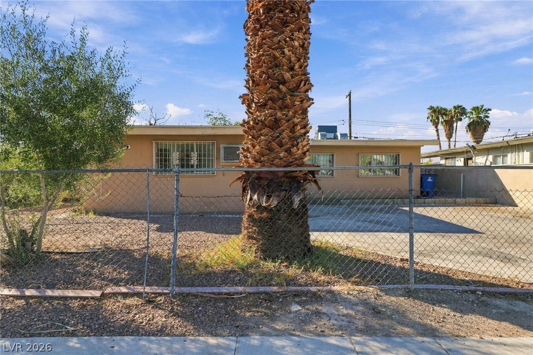 2521 Perliter Avenue, North Las Vegas, NV 89030 A classic stucco exterior is secured by fencing under sunny desert skies.