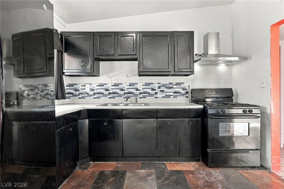 2521 Perliter Avenue, North Las Vegas, NV 89030 Dark cabinetry and a tiled backsplash define this functional cooking space with stone-patterned floors.