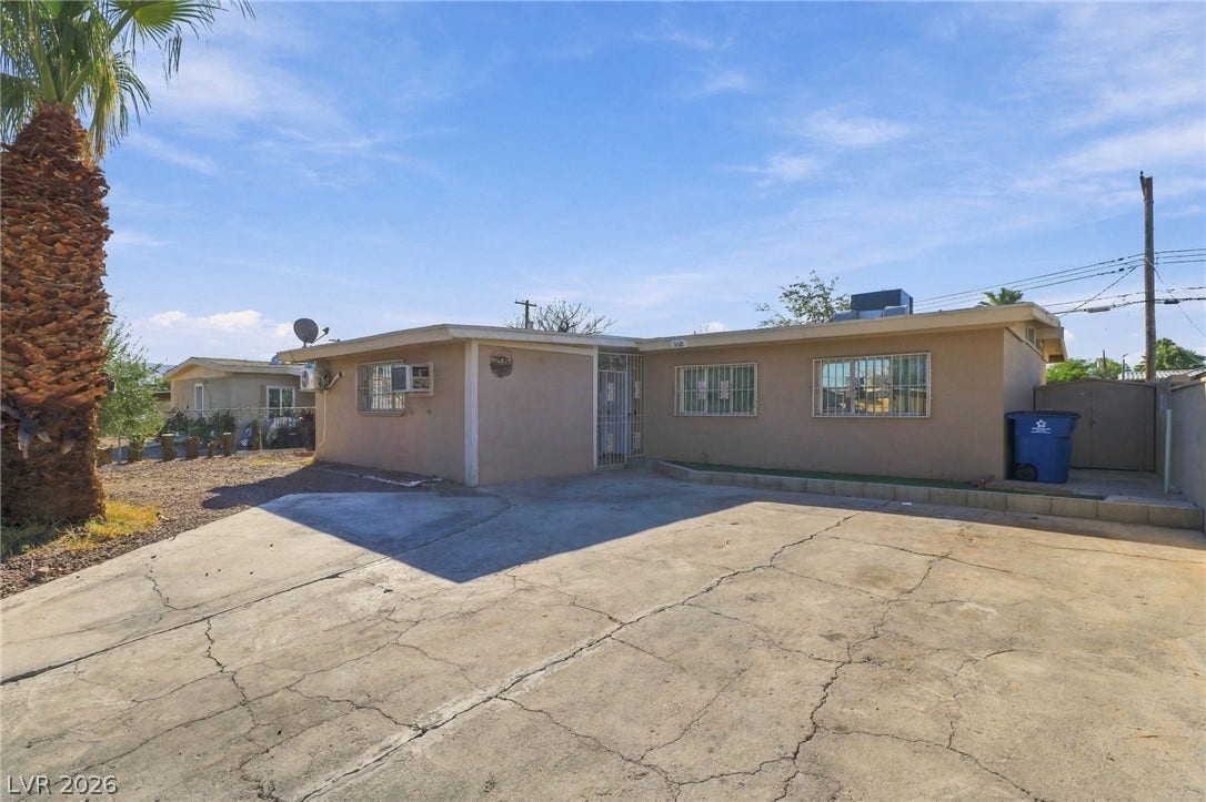 2521 Perliter Avenue, North Las Vegas, NV 89030 An expansive concrete driveway leads to this single-story residence under clear desert skies.