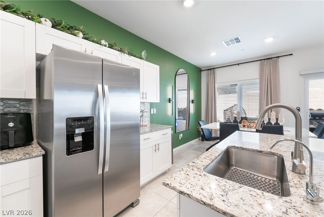 10958 Cheshire Woods Avenue, Las Vegas, NV 89166 Granite countertops and clean white cabinetry frame this modern, light-filled kitchen space.