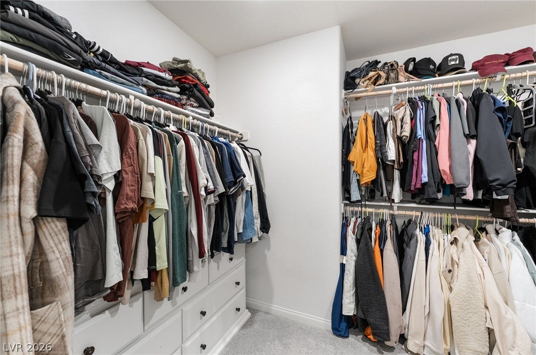 10958 Cheshire Woods Avenue, Las Vegas, NV 89166 A spacious walk-in closet includes carpet flooring alongside integrated shelving and dresser storage.