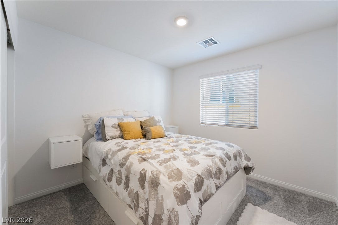 10958 Cheshire Woods Avenue, Las Vegas, NV 89166 A quiet bedroom features plush carpeting and a large window for natural illumination.