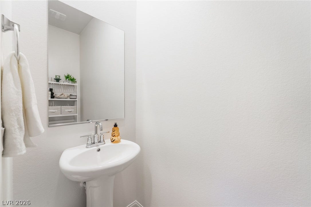 10958 Cheshire Woods Avenue, Las Vegas, NV 89166 A classic pedestal sink pairs with a frameless mirror in this clean powder room.