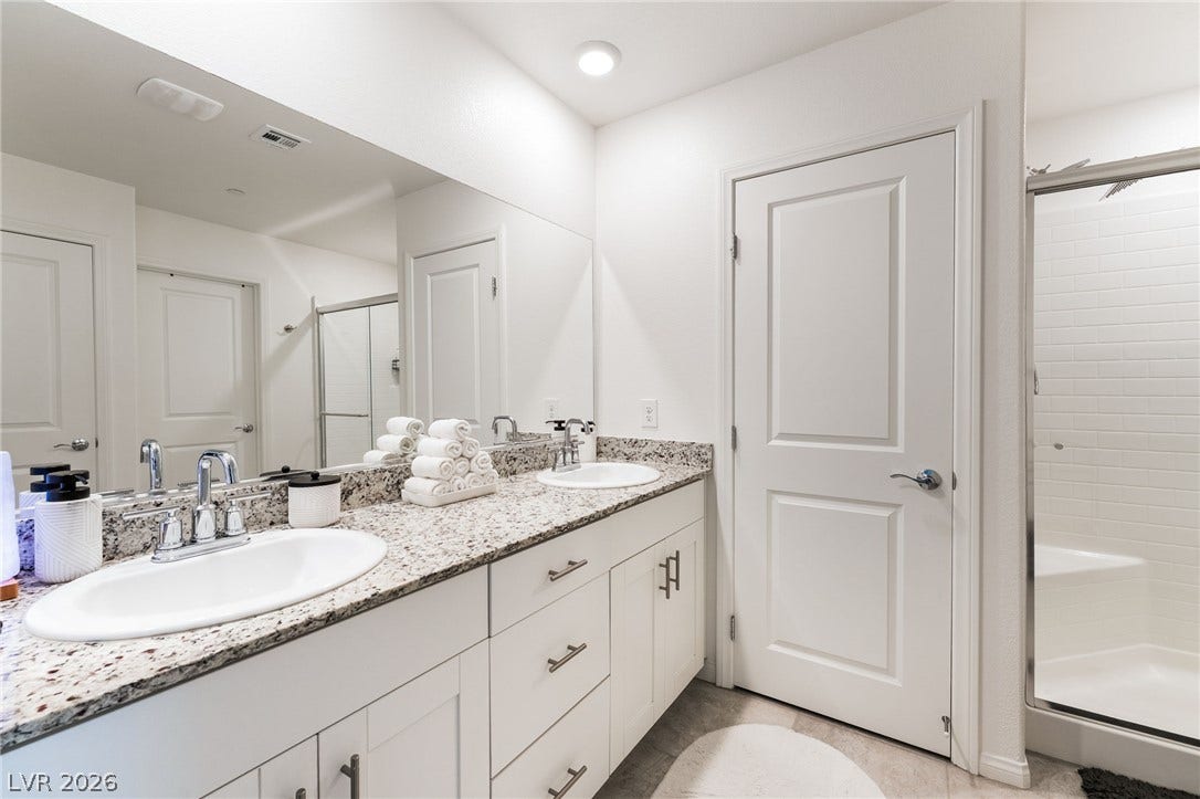 10958 Cheshire Woods Avenue, Las Vegas, NV 89166 A spacious double vanity with granite countertops anchors this modern bathroom space.