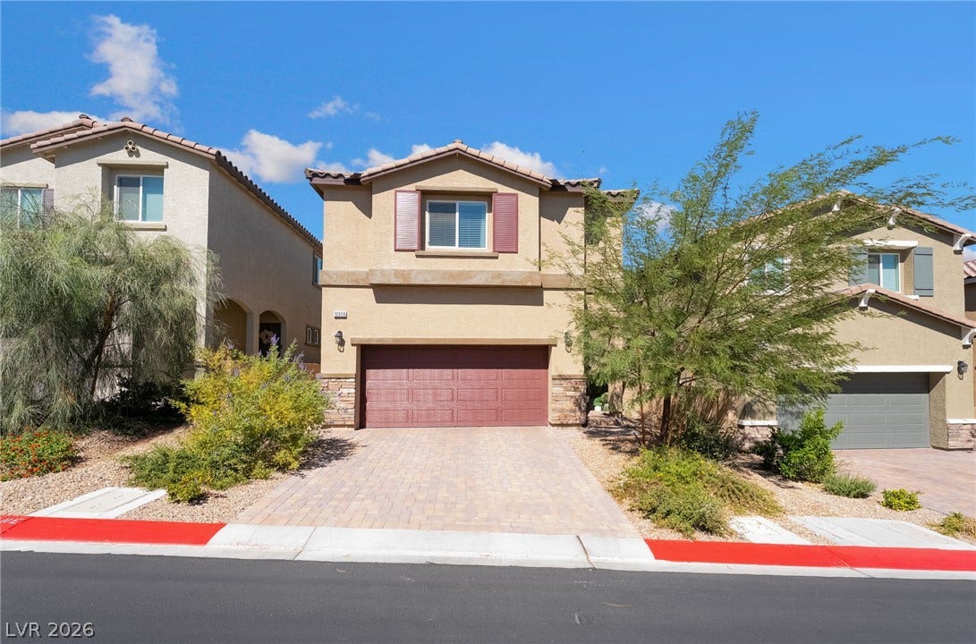 10958 Cheshire Woods Avenue, Las Vegas, NV 89166 An inviting two-story exterior showcases classic stucco walls and a paved driveway leading to the garage.