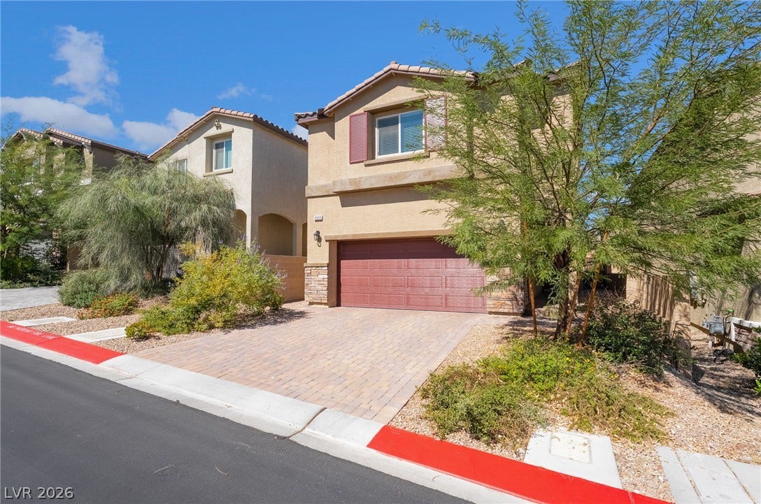 10958 Cheshire Woods Avenue, Las Vegas, NV 89166 Mediterranean-inspired stucco exterior features a paved driveway leading to a two-car garage.