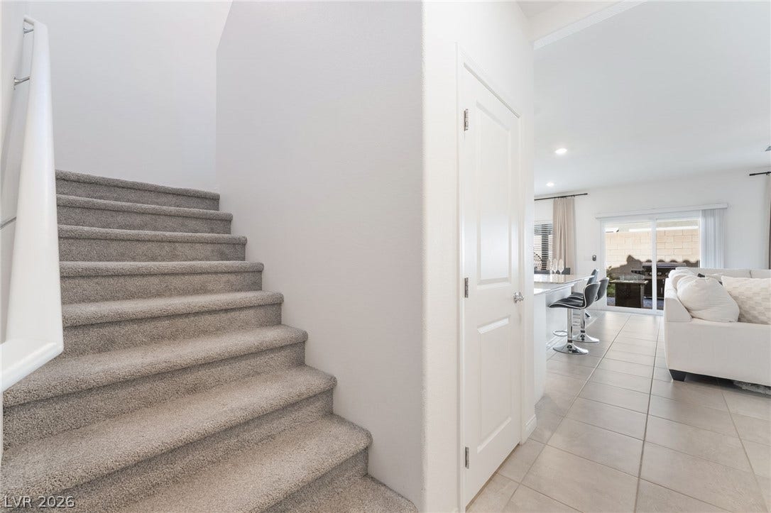 10958 Cheshire Woods Avenue, Las Vegas, NV 89166 Carpeted stairs ascend from a tiled hallway leading into an open-concept living area.