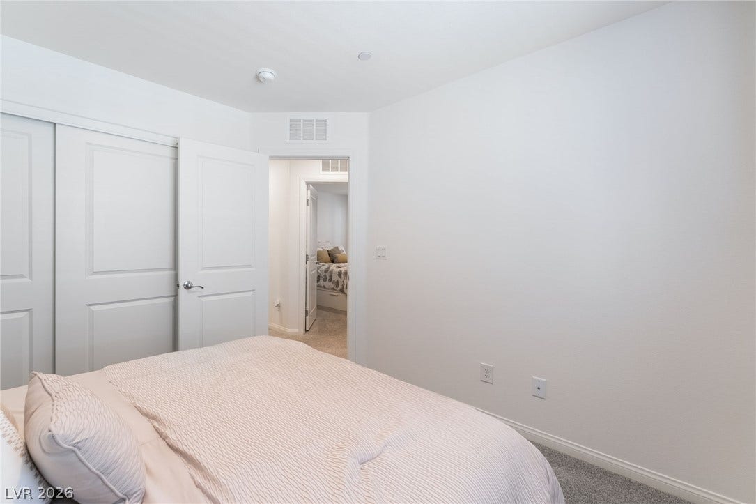 10958 Cheshire Woods Avenue, Las Vegas, NV 89166 An inviting bedroom features plush carpeting and crisp white walls.