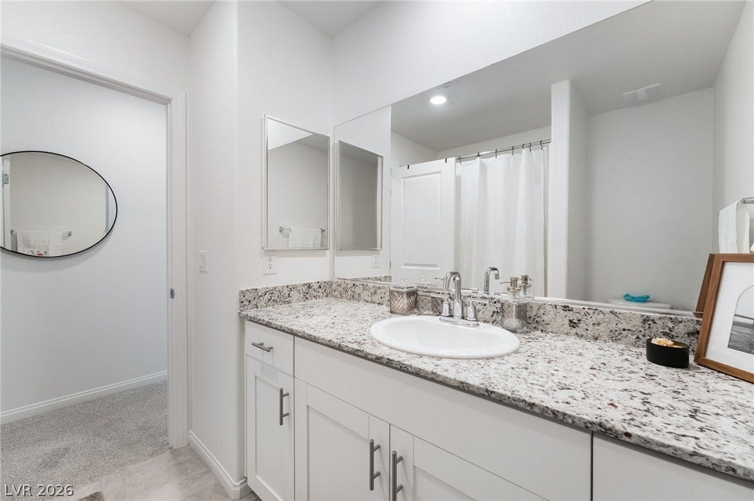 10958 Cheshire Woods Avenue, Las Vegas, NV 89166 Polished stone counters and clean lines elevate this modern vanity space.
